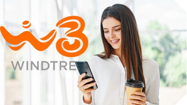 Immagine di donna sorridente che utilizza uno smartphone con logo WindTre 3 e beve caffè, ambiente luminoso e naturale, promozione servizi di telefonia mobile e internet in Italia.