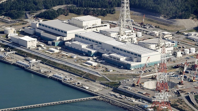 Centrale nucleare con grandi strutture e torri di raffreddamento, situata vicino all'acqua, che fornisce energia sicura e sostenibile, simbolo di tecnologia avanzata nel settore energetico.