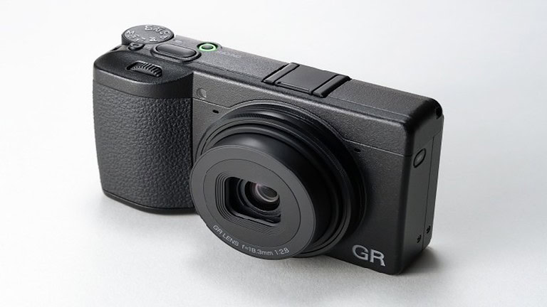 Alt text: Fotocamera digitale compatta di colore nero con obiettivo grandangolare e pulsanti di controllo, ideale per fotografia di alta qualità.