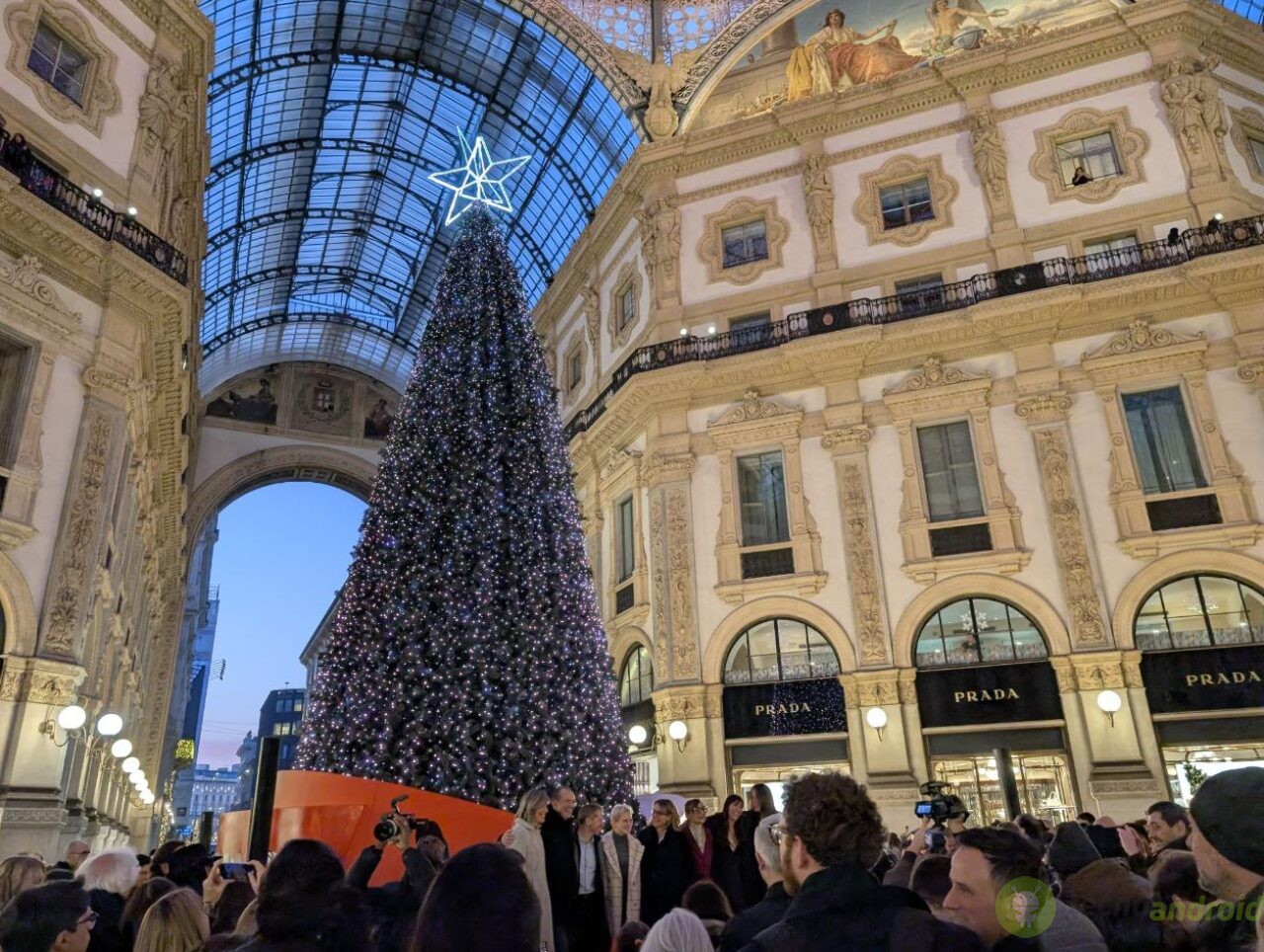 Albero Natale Galleria Milano. Albero di Natale decorato in una luxury shopping mall a Milano, con grande folla di visitatori, luci scintillanti, ambiente festoso, e negozi di alta moda come Prada, atmosfera natalizia elegante e glamour.