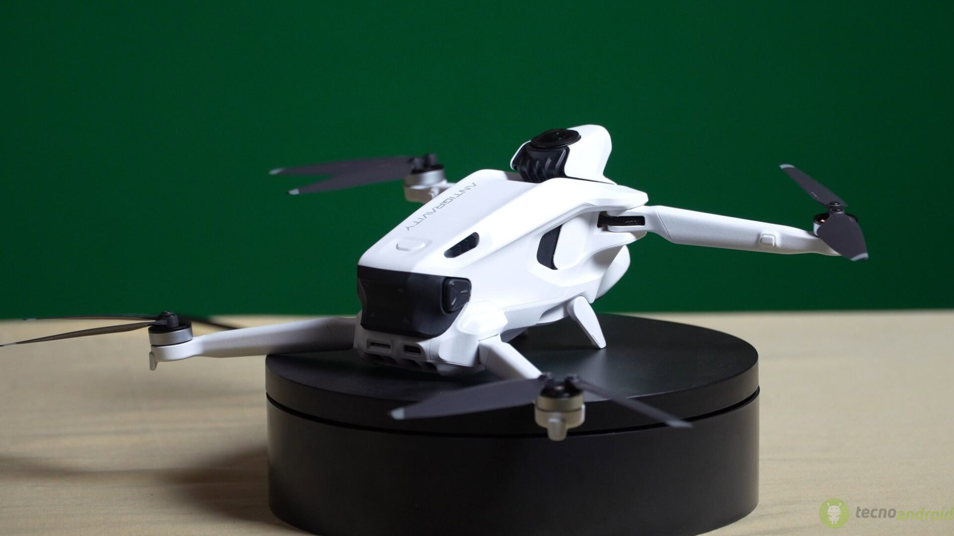 Drone bianco con quattro eliche su base nera, posizionato su un supporto nero, utilizzato per riprese aeree e fotografia con notevoli funzionalità di stabilità e controllo.