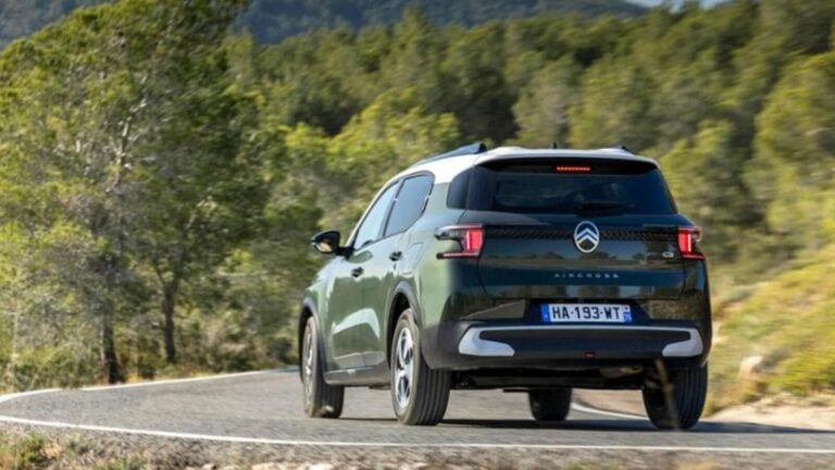 Auto ibrida Citroën Ami 3 in movimento su strada di montagna con sfondo verde e natura, modello innovativo e sostenibile, perfetto per spostamenti urbani ed eco-friendly.