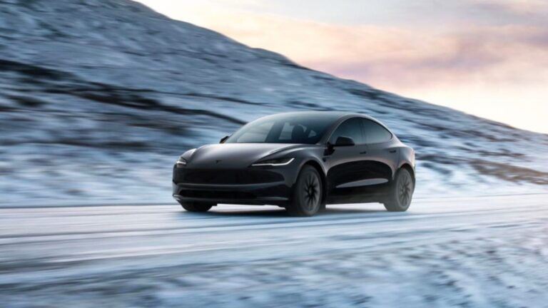 Auto Tesla elettrica nera che percorre una strada innevata con uno sfondo di montagne e cielo al tramonto, simbolo di tecnologia e mobilità sostenibile.