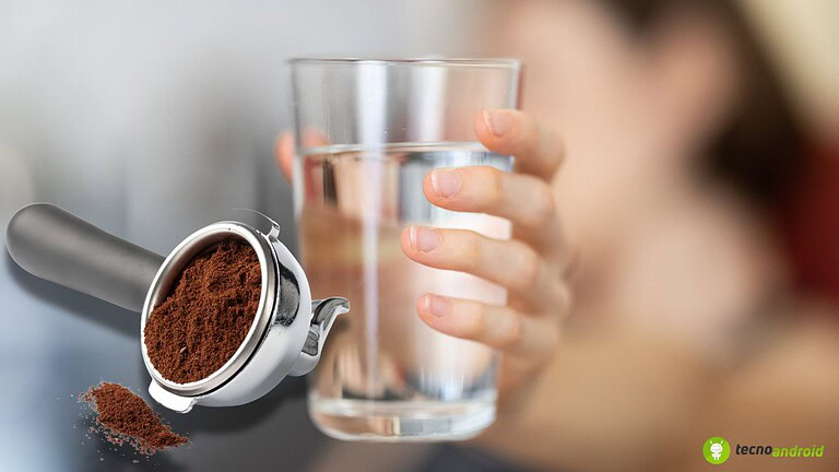 Macchina da caffè con polvere di caffè e una persona che tiene un bicchiere d'acqua.