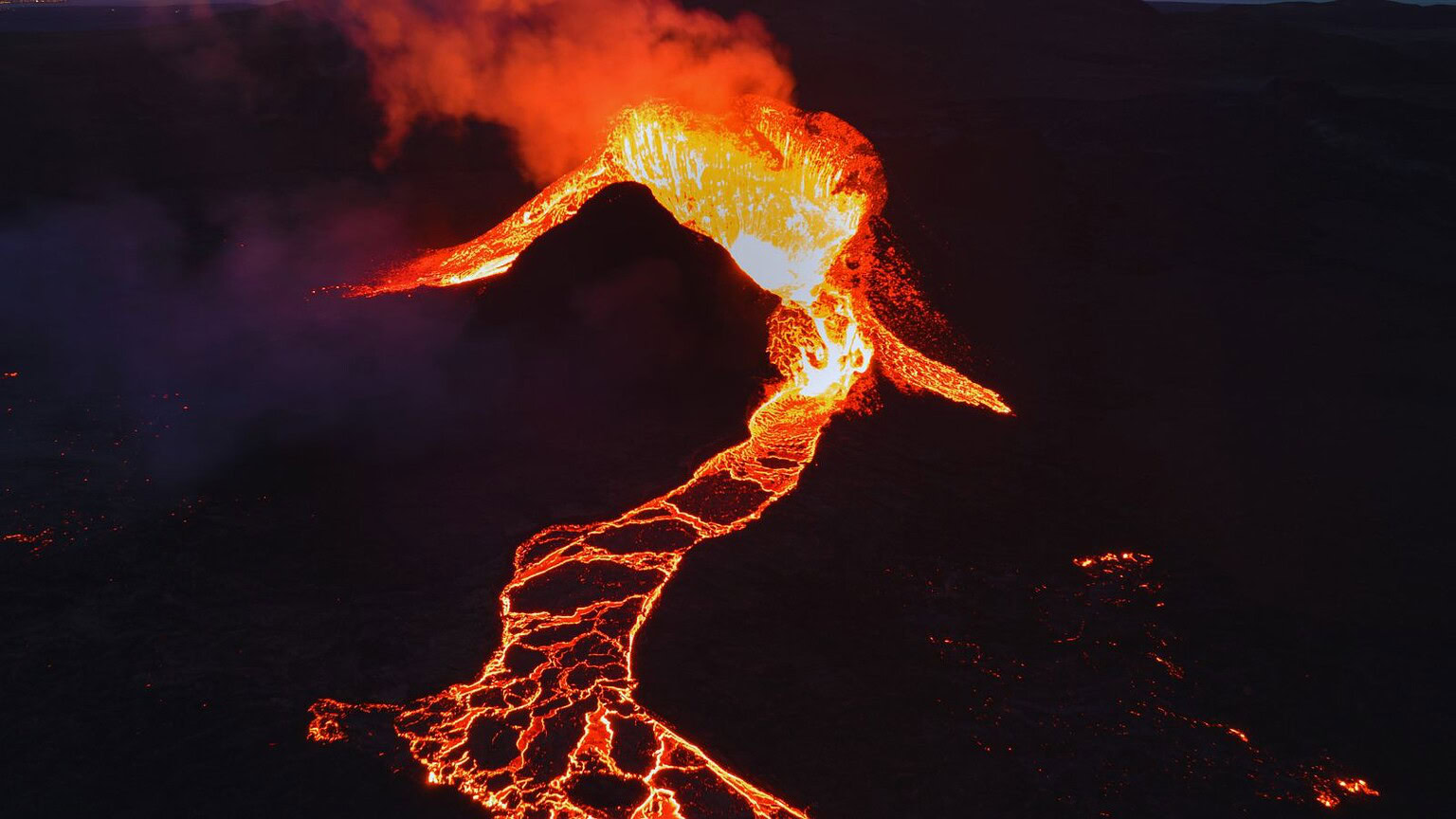 Immagine di un'eruzione vulcanica con lava incandescente, fumo e magma che defluisce dalla bocca del vulcano, simbolo di potenza naturale e fenomeno geologico impressionante.
