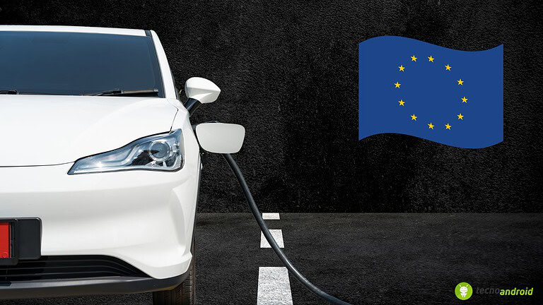 Auto elettrica bianca collegata alla presa di ricarica, simbolo di mobilità sostenibile e tecnologia verde, con bandiera dell'Unione Europea sul muro, rappresentando l'innovazione nel settore automobilistico europeo.