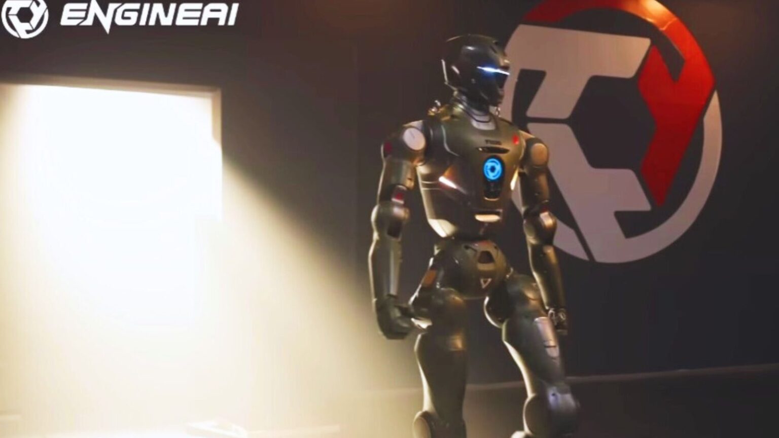 Robot futuristico umanoide nero e argento con luci blu, in piedi in un ambiente moderno con logo tecnico sullo sfondo, rappresenta innovazione e progresso nel campo della robotica.