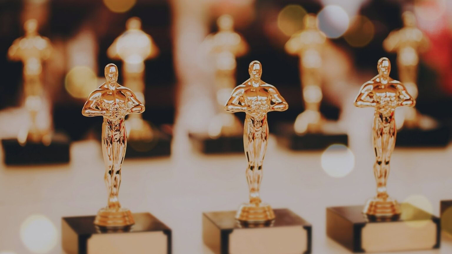 Statue di Oscar in oro rosa, simbolo di Hollywood, sono al centro di questa immagine, rappresentando i riconoscimenti cinematografici più prestigiosi.