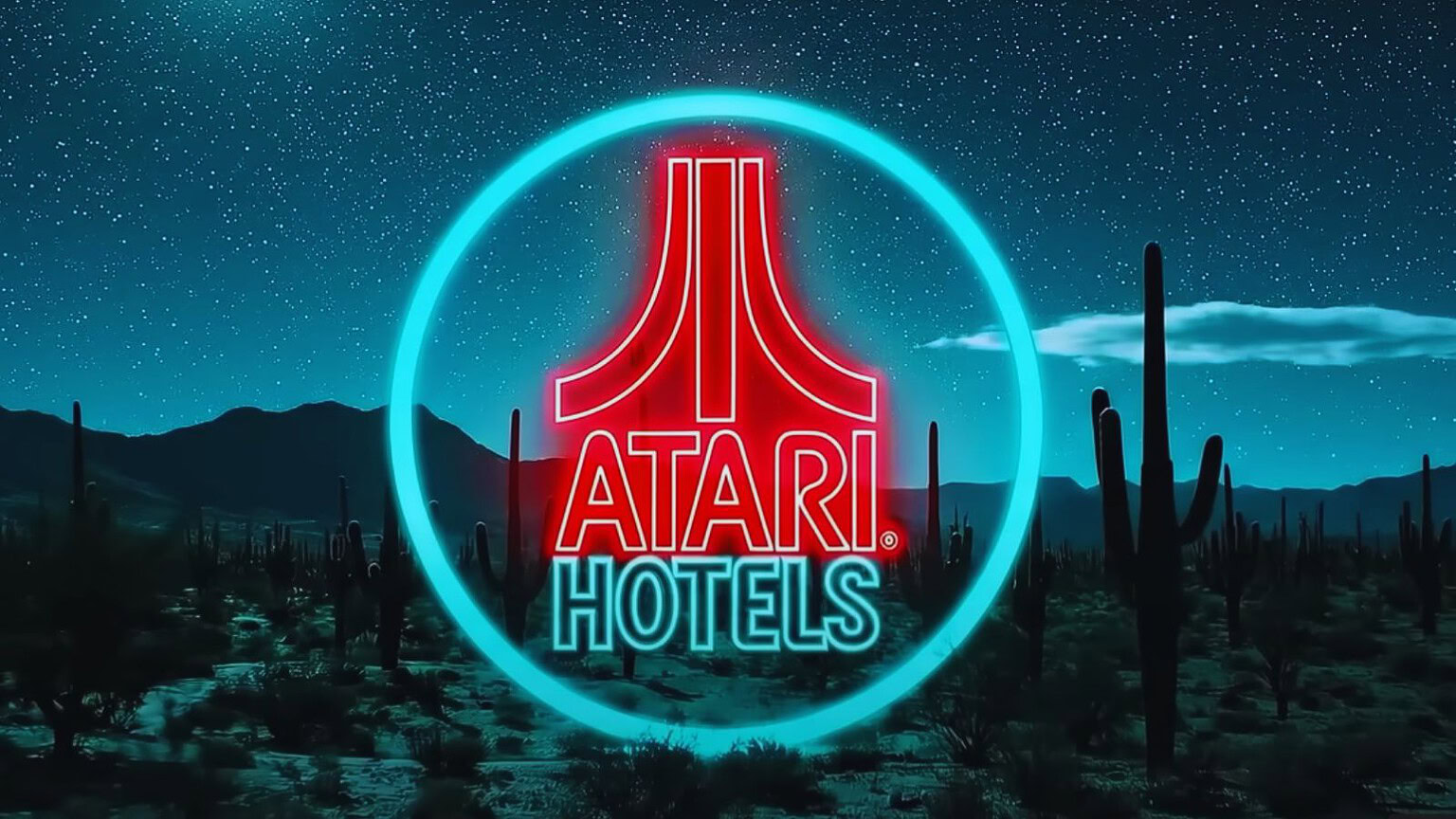 Altezza di un logo Atari Hotels illuminato in uno scenario desertico notturno con cactus e montagne sullo sfondo.