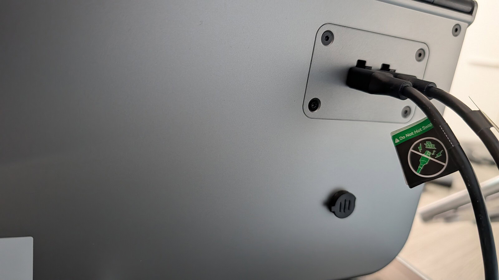 Creality K2 Pro Combo - immagine 20 Immagine di un monitor da ufficio con cavi di alimentazione collegati e adesivo di sicurezza per evitare surriscaldamenti.