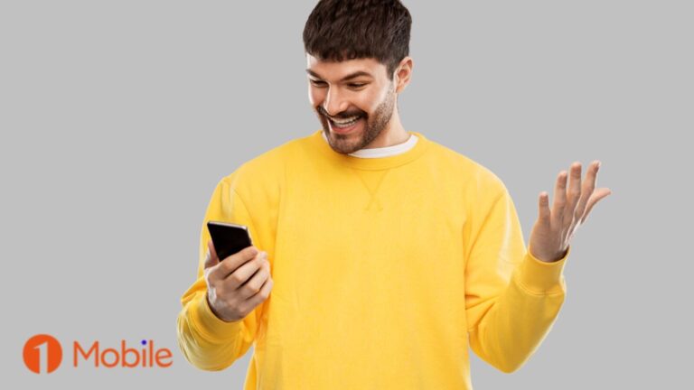 Immagine di un uomo che sorride mentre usa uno smartphone, con sfondo grigio e logo 1Mobile in basso a sinistra.