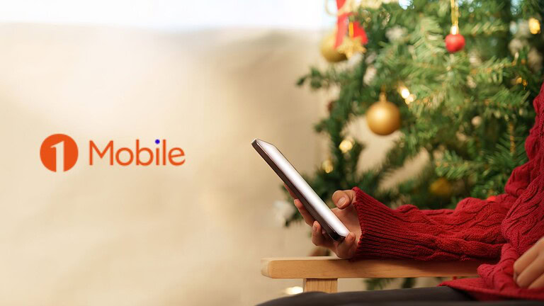 Smartphone in mano vicino all'albero di Natale decorato.