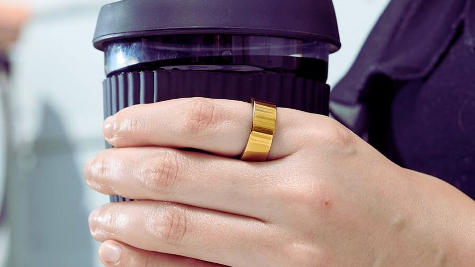 Alt text: Mani che tengono una tazza di caffè portatile, ideale per chi ama il caffè ovunque, con un focus sul design compatto e pratico.