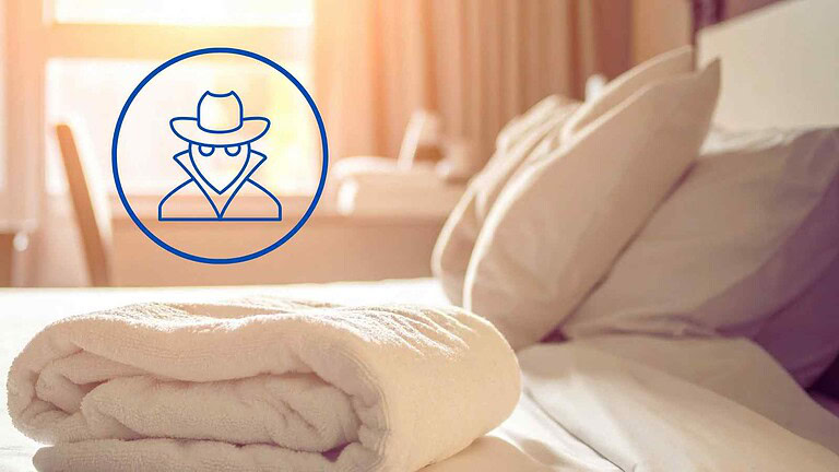 Immagine di un letto con biancheria e una pila di asciugamani, con un'icona di un personaggio misterioso e mascherato in stile detective o hacker digitale, indicante sicurezza o privacy online.