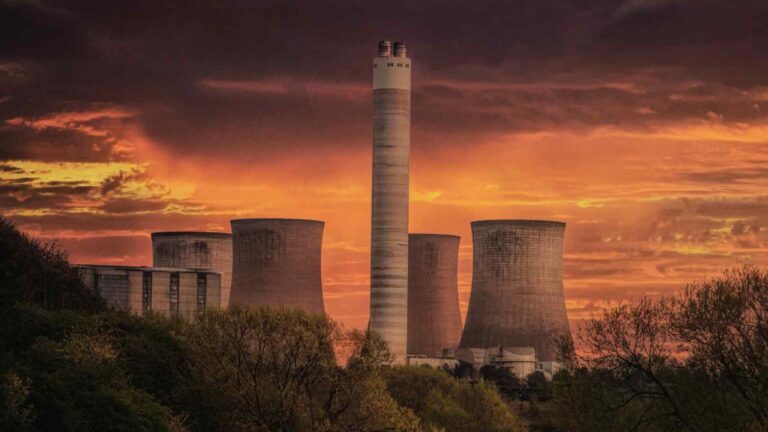 Immagine di una centrale nucleare al tramonto con nuvole colorate all'orizzonte, evidenziando energia e innovazione nel settore energetico.