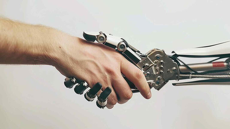 Robot umanoide con mano umana e circuito meccanico, rappresenta evoluzione in robotica, intelligenza artificiale e innovazione tecnologica.