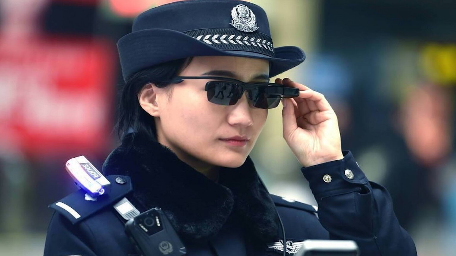 Poliziotta in uniforme da polizia con occhiali da sole tecnologici all'aperto.