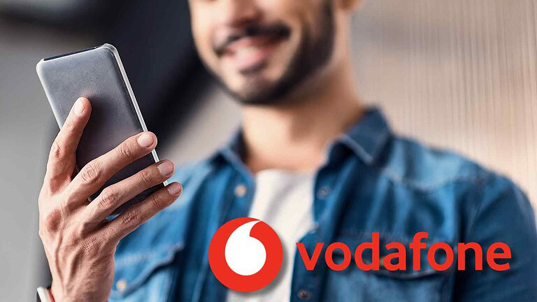 L'immagine mostra un uomo felice che utilizza uno smartphone con loghi Vodafone, simbolo di connessione e innovazione digitale, perfetta per notizie e approfondimenti sul mondo della telefonia e dei dispositivi mobili.